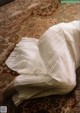 A woman in a white dress laying on a rug.