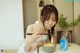 A woman sitting at a table eating a bowl of noodles.