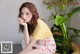 A woman sitting on the floor next to a potted plant.