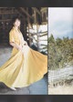 A woman in a yellow dress standing in front of a barn.