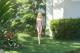 A woman in a bikini walking through a lush green garden.