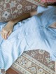 A woman laying on a rug wearing a blue and white checkered dress.