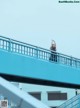 A woman standing on top of a blue bridge.