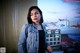 A woman in a denim jacket standing on a balcony.