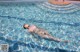 A naked woman floating in a swimming pool.